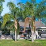 A charming home surrounded by palm trees, featuring a cozy patio ideal for relaxation during your holiday village RV park stay.