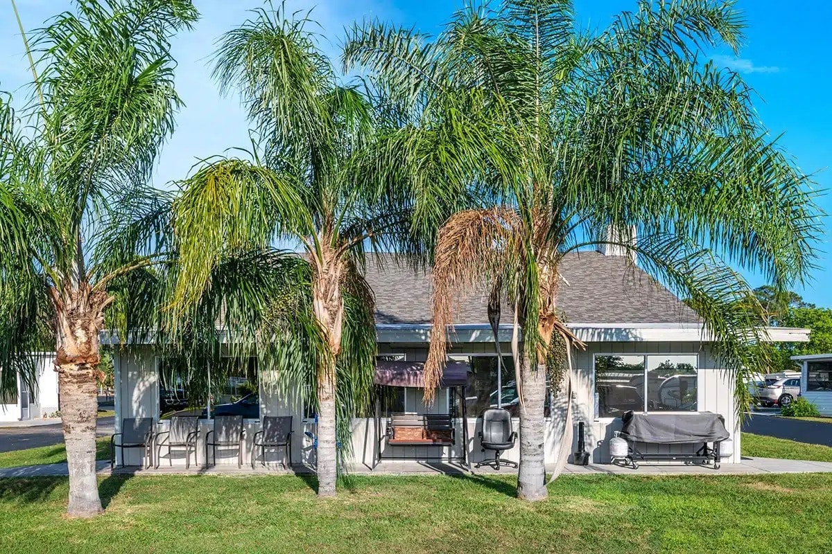 A charming home surrounded by palm trees, featuring a cozy patio ideal for relaxation during your holiday village RV park stay.