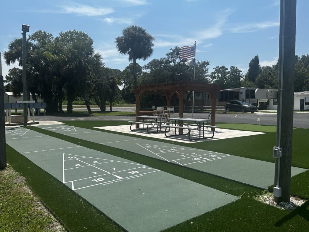 A serene park featuring a picnic table and a shuffleboard area in Holiday Village RV Park.