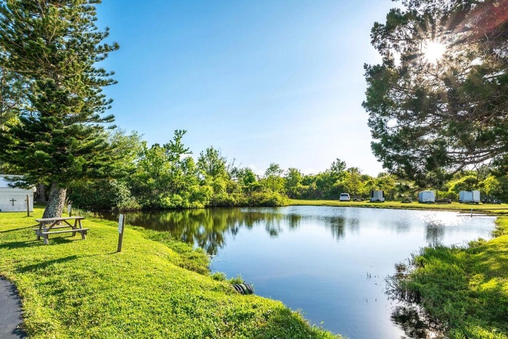 A serene pond surrounded by a picnic area at Holiday Village RV Park, perfect for relaxation and outdoor gatherings.