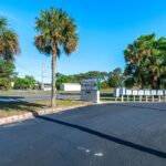 The entrance of a parking lot featuring palm trees, inviting visitors to explore the amenities of Holiday Village RV Park.