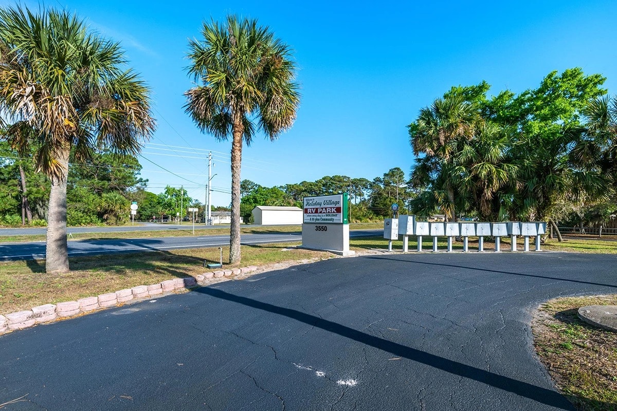 The entrance of a parking lot featuring palm trees, inviting visitors to explore the amenities of Holiday Village RV Park.