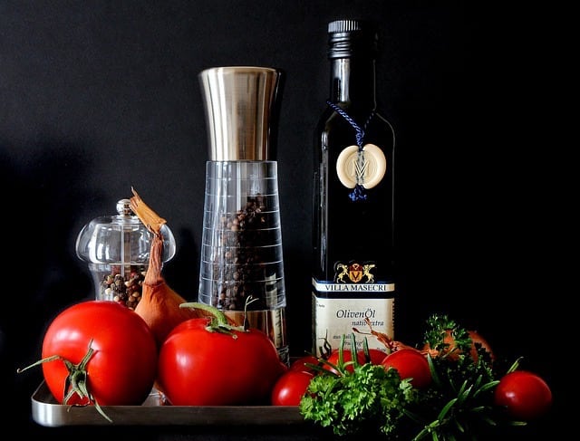 A tray displaying fresh tomatoes, garlic, olive oil, and an assortment of spices, ready for culinary preparation.