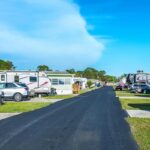 A row of RV parks in Titusville featuring parked cars and trailers under clear blue skies.