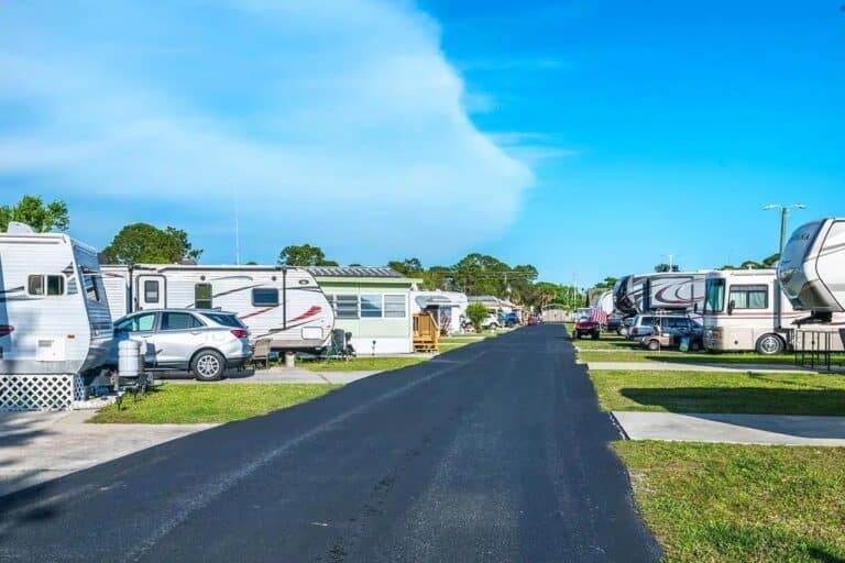 A row of RV parks in Titusville featuring parked cars and trailers under clear blue skies.