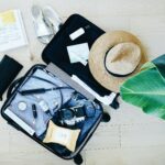 A suitcase adorned with a stylish hat, sunglasses, and various travel essentials, ready for an adventure.