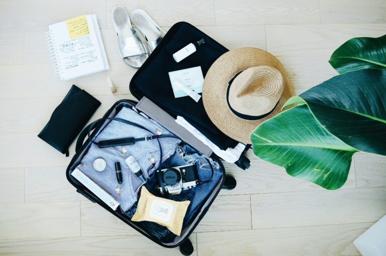 A suitcase adorned with a stylish hat, sunglasses, and various travel essentials, ready for an adventure.