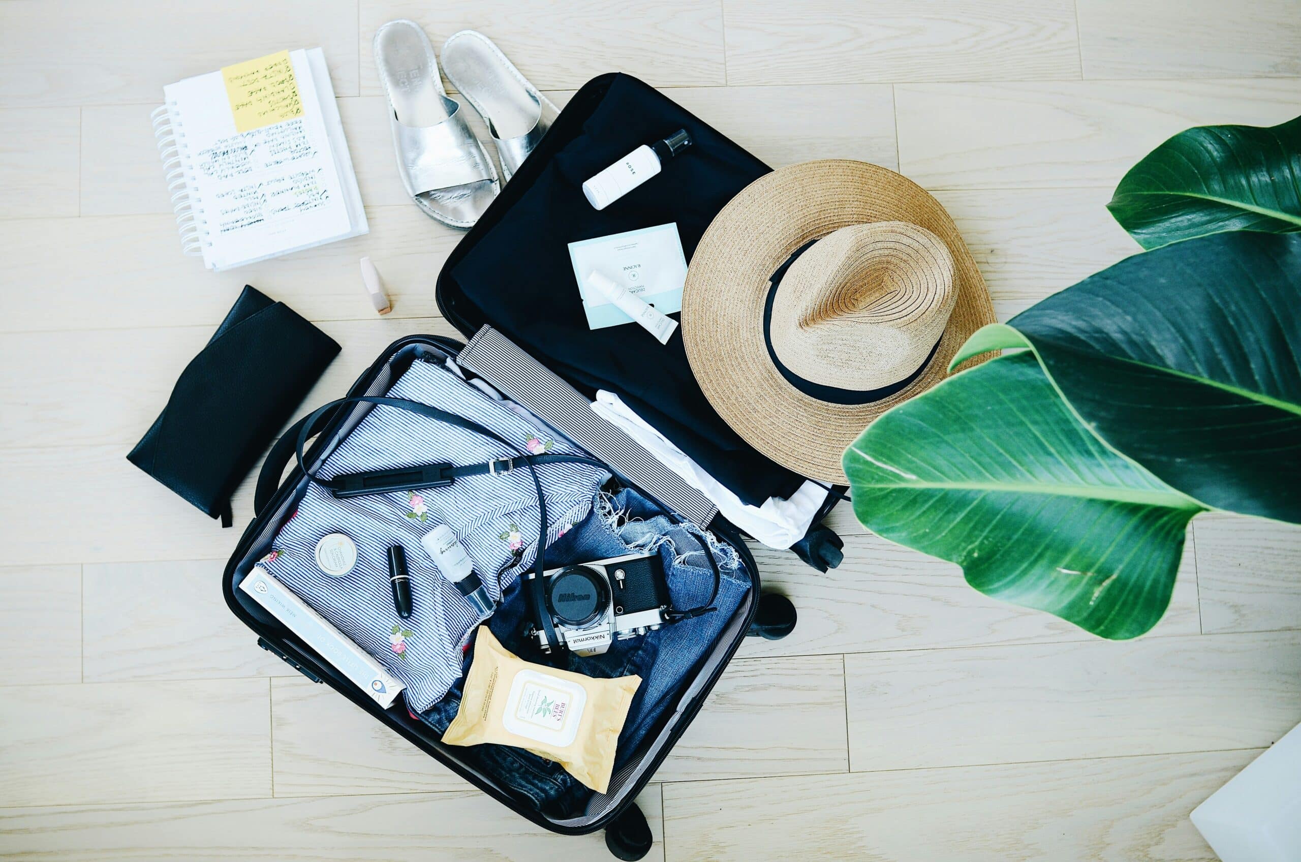 A suitcase adorned with a stylish hat, sunglasses, and various travel essentials, ready for an adventure.